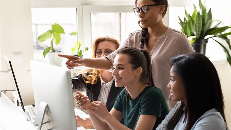 Four women looking at desktop computer screen.