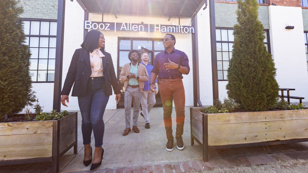 A Woman and three men emerging from a Booz Allen office