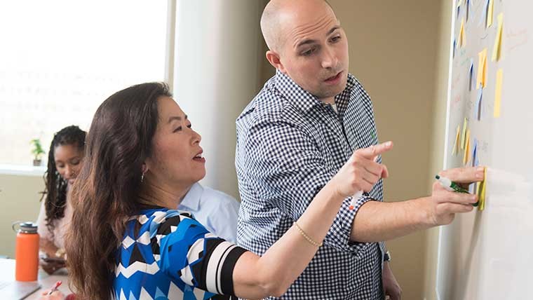 Two people discussing ideas written on a whiteboard