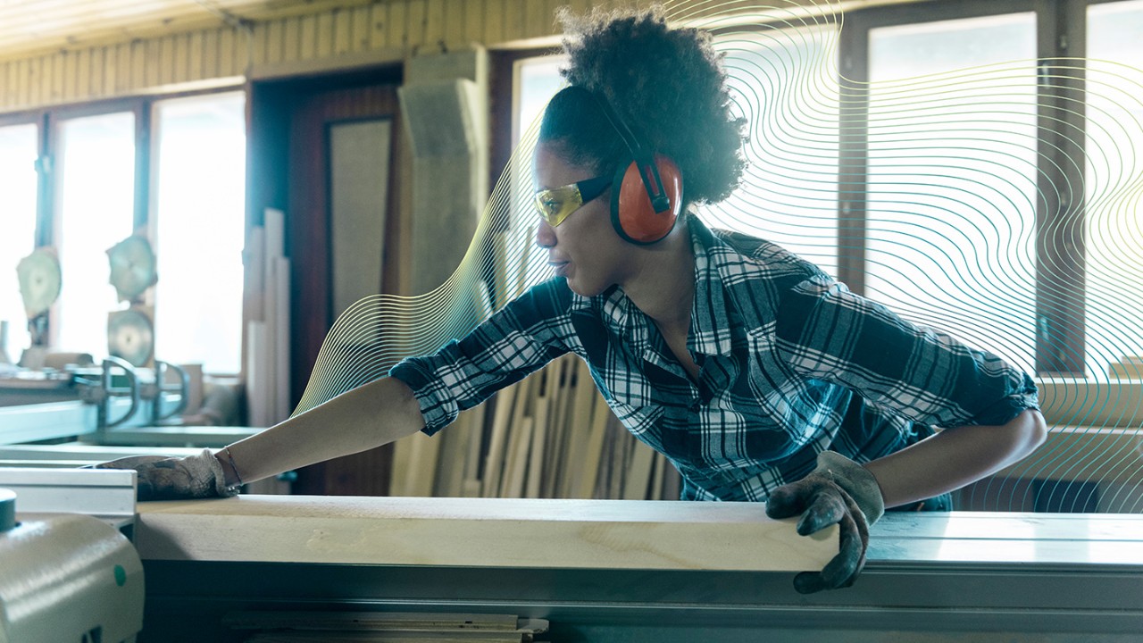 Woman sawing wood in a workshop