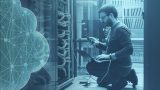 A man kneeling down in a networking closet.