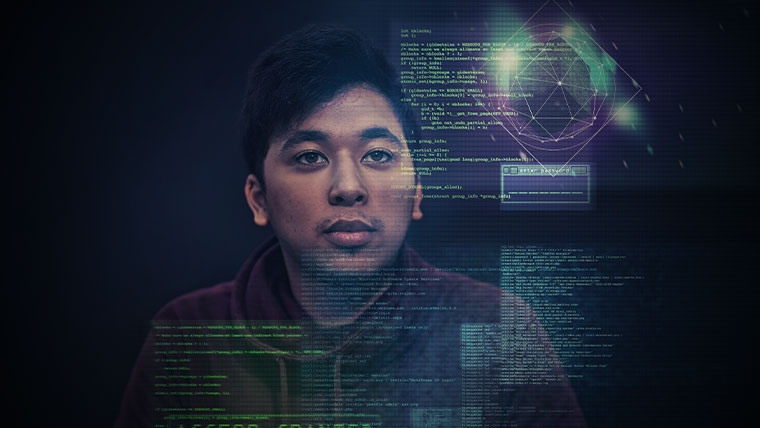 Man sitting at desk with multiple computer screens in front of him.